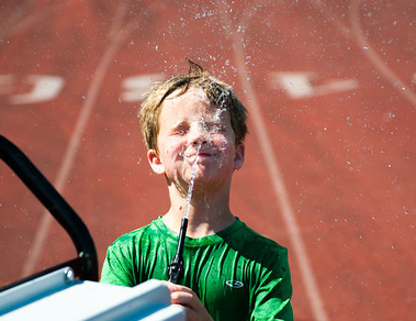 Montclair Soccer Camp presents a kid hosing down with water.