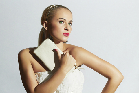 Beautiful blond woman in white dress.Fashion Stylish girl with white clutch.Red lips.Bride