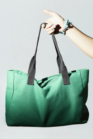Textile handbag in woman hand. fashion green sport bag