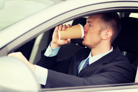 Man drinking coffee while driving the car